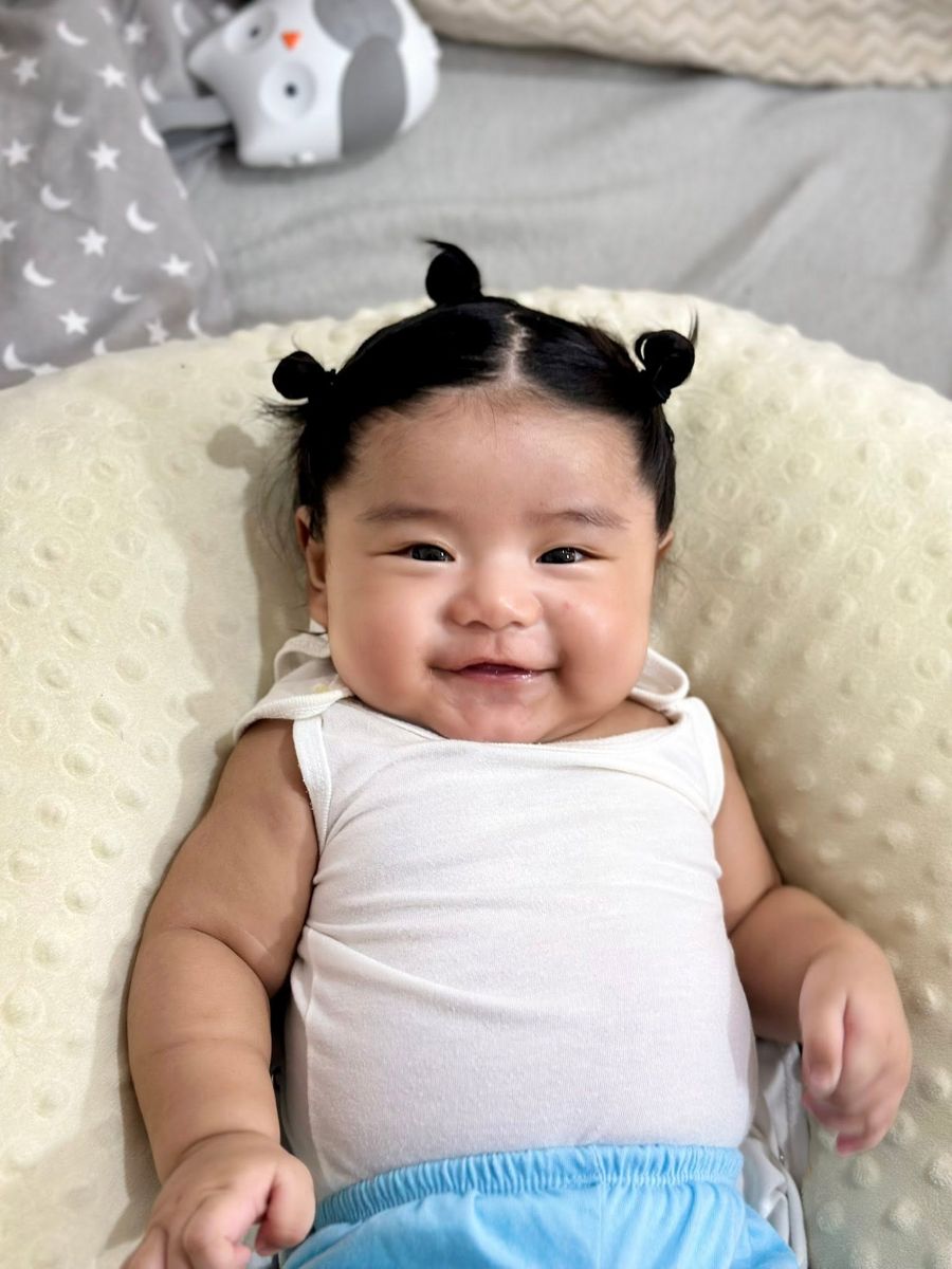 Baby smiling happily with two little hair buns
